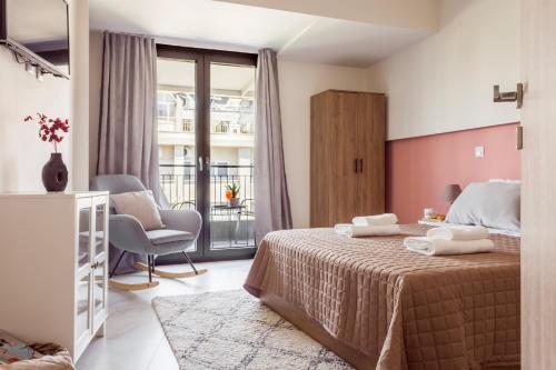 a bedroom with a bed and a chair and a window at AEONS - Hotelia Hospitality Group in Thessaloniki