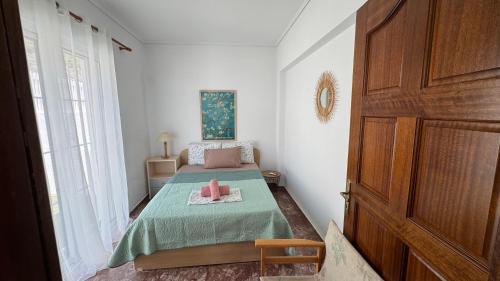 a small bedroom with a bed with a green blanket at Amazing villa with a magic view to the Aegean in Dhaskalión
