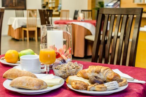 a table with two plates of bread and orange juice at Hospedería Pax in León