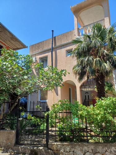 un edificio con una palmera delante en Guesthouse PLANINA, en Sutomore