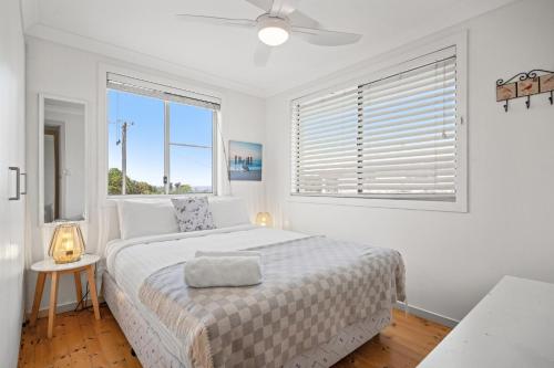a white bedroom with a large bed with a window at At the Beach - Lennox Head in Lennox Head