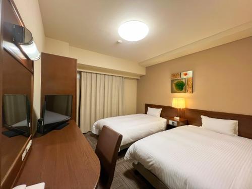 a hotel room with two beds and a flat screen tv at Hotel Route-Inn Hirosaki Joto in Hirosaki