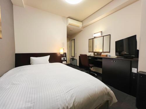 a bedroom with a bed and a desk and a television at Hotel Route-Inn Hirosaki Joto in Hirosaki