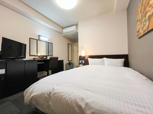 a bedroom with a large white bed and a desk at Hotel Route-Inn Hirosaki Joto in Hirosaki