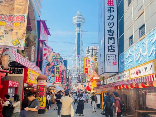 una multitud de personas caminando por una concurrida calle de la ciudad en バンデホテル in なんば, en Osaka