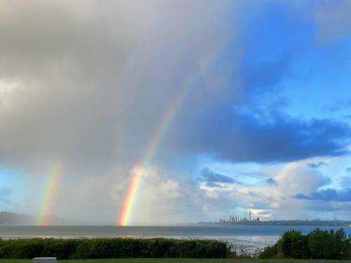 ein Regenbogen am Himmel über dem Wasser in der Unterkunft Auckland Luxury Seafront House in Auckland