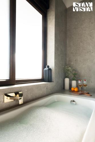 a bath tub in a bathroom with a window at StayVista at Casa Ti Amo with WiFi, AC, Pool, BBQ in Siolim