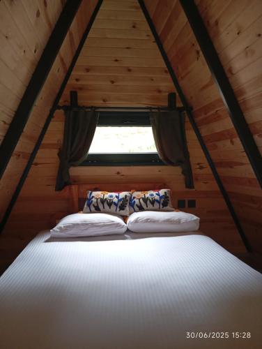 a bed in a wooden cabin with a window at La Vica Bungalow in Rize