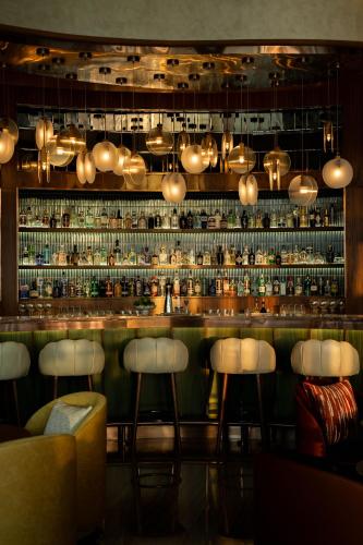 a bar with white stools in front of a shelf at Rosewood Abu Dhabi in Abu Dhabi