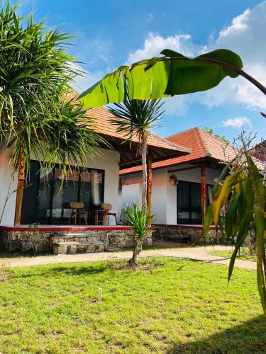 a house with a palm tree in front of it at Ceningan Cliff Cottages in Nusa Lembongan
