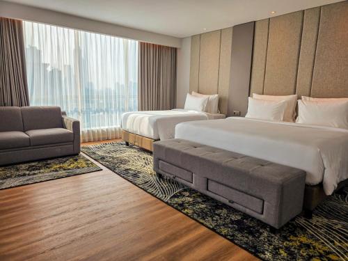 a hotel room with two beds and a couch at The Grand Platinum Jakarta in Jakarta
