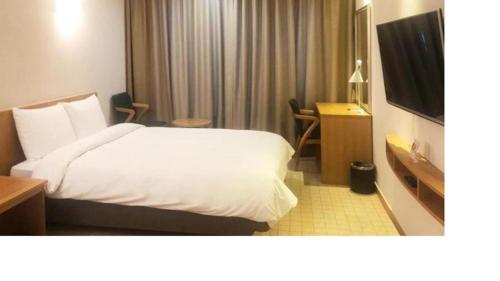 a hotel room with a bed and a television at Mstay Hotel in Seogwipo