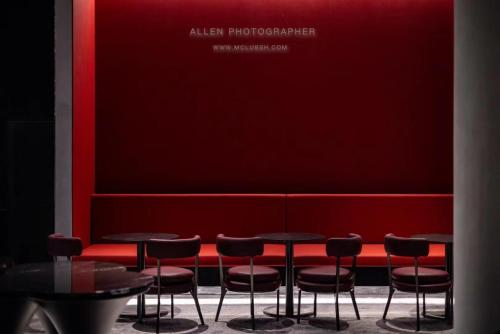 a row of tables and stools in a room with a red wall at Novotel Kunming City Center in Kunming
