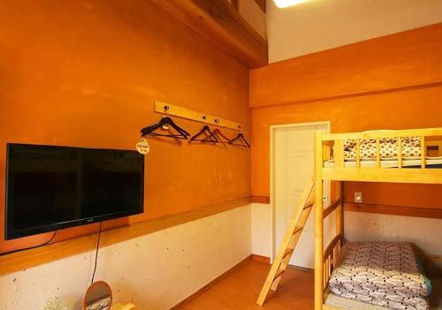 a bedroom with a flat screen tv and a bunk bed at Dorandoran Guesthouse in Gyeongju