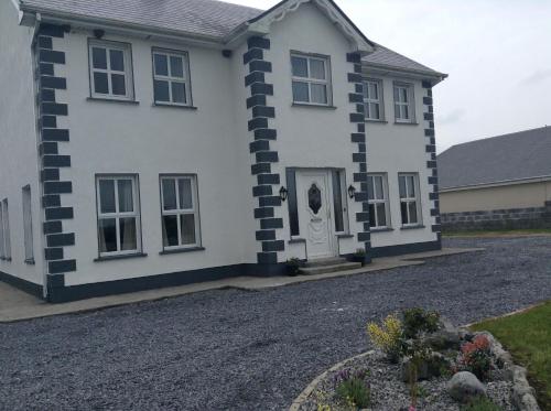 a white house with black and white stripes on it at Cranagh House, Kinvara. in Loughcurra