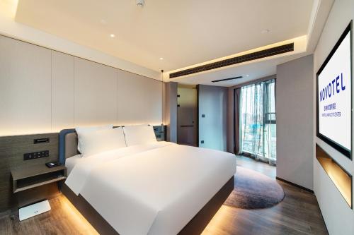 a bedroom with a white bed and a tv at Novotel Kunming City Center in Kunming