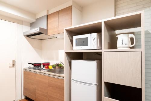 a kitchen with a white refrigerator and a microwave at BON Condominium Umeda in Osaka
