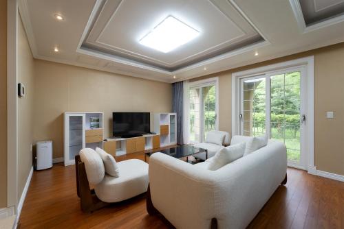 a living room with white couches and a tv at Kylin Villa resort Jeju in Seogwipo