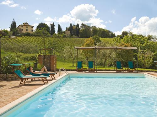a woman sitting in a chair next to a swimming pool at Relais Villa Monte Solare Wellness & SPA in Panicale