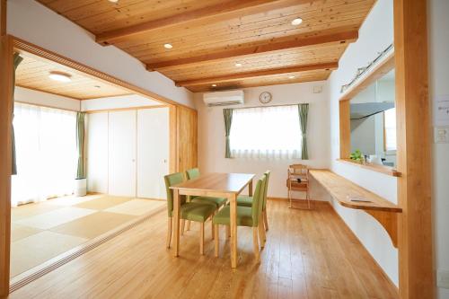 a dining room with a wooden table and green chairs at 貸切 KIX 25min Family-Friendly Hinoki House Free P in Kishiwada
