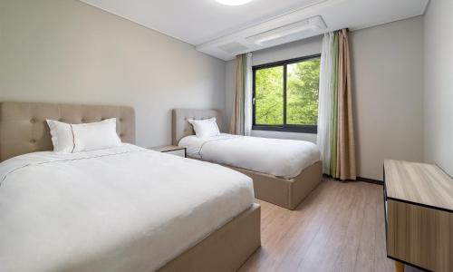 a hotel room with two beds and a window at Kylin Villa resort Jeju in Seogwipo