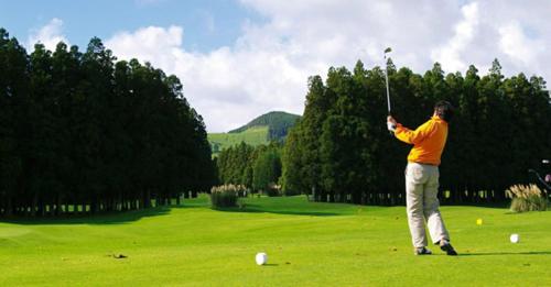 a man swinging a golf club on a field at Casa da Beija - House Azores in Furnas