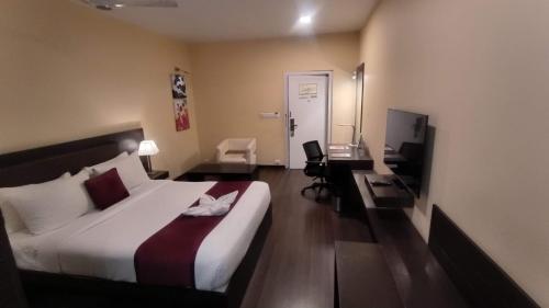 a hotel room with a bed and a desk with a computer at THE WOODROSE in Bengaluru