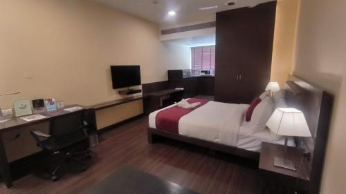 a hotel room with a bed and a desk and a computer at THE WOODROSE in Bengaluru