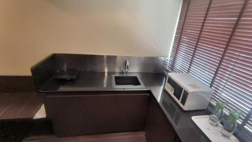 a kitchen with a counter with a sink and a microwave at THE WOODROSE in Bengaluru