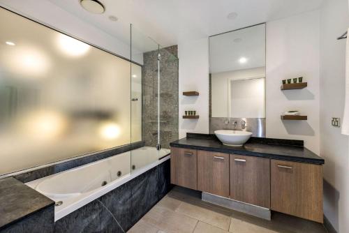ein Badezimmer mit Badewanne, Waschbecken und Dusche in der Unterkunft Belle Escapes 228-229 Luxury Beachfront Resort Palm Cove in Palm Cove