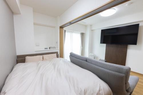 a bedroom with a bed and a flat screen tv at Tomattoco KASUMI in Yamagata