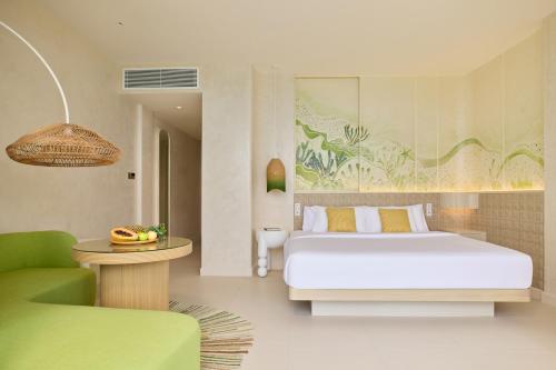 a bedroom with a bed and a green chair at Centara Mirage Lagoon Maldives in Nakachchafushi
