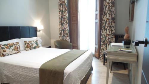 Habitación de hotel con cama, escritorio y cama en Hotel Moderno Puerta del Sol, en Madrid