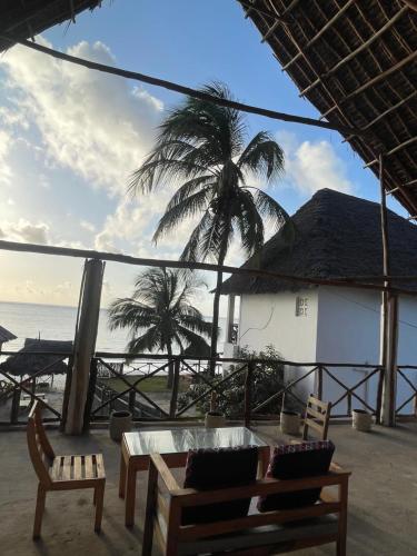 a building with a table and chairs and a palm tree at Zanzibar beach escape 1&2 in Bwejuu