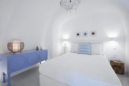 a white bedroom with a blue bed and a blue nightstand at Olea Cave House in Imerovigli