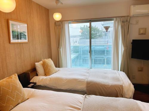 una camera d'albergo con due letti e una finestra di 301 湘南 鵠沼海岸 サーフィンに最適なビーチ近くの独立型アパート a Fujisawa