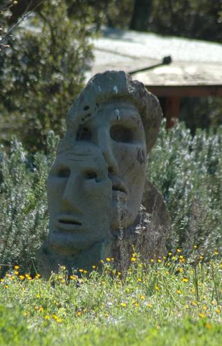 a statue of a head in a field of flowers at Il Nuraghe del lago Coghinas in Oschiri