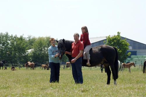 a man and a woman with a child on a horse at Filippus Vakantiehoeve in Maldegem