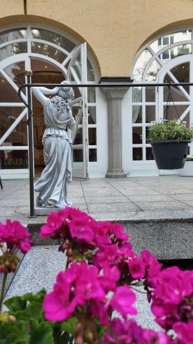 a statue of a woman standing next to pink flowers at Hotel Aurbacher Hof GmbH in Munich