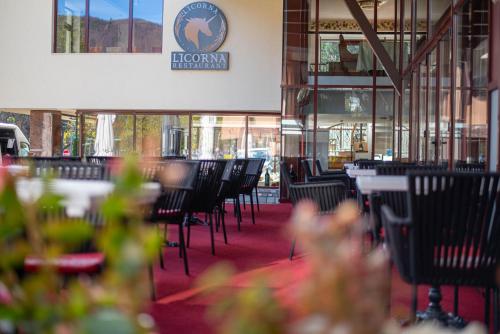 a restaurant with black chairs and tables and windows at Hotel Anda in Sinaia