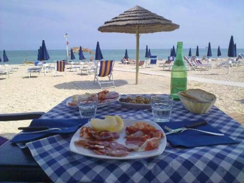 a table with two plates of food on the beach at Sun and Sand in Civitanova Marche