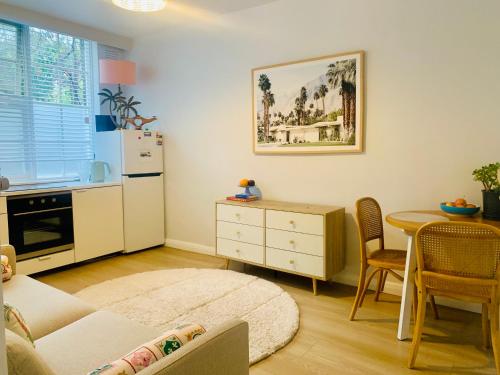 a kitchen with a white refrigerator and a table with chairs at Cosy One Bedroom Apt Next to Park! in Melbourne