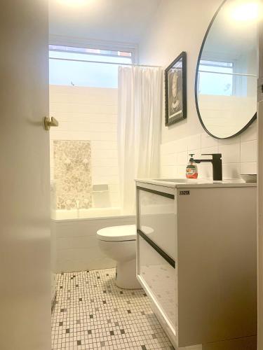 a bathroom with a toilet and a sink and a mirror at Cosy One Bedroom Apt Next to Park! in Melbourne