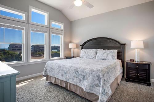 a bedroom with a bed with two lamps and windows at 3054 - Latitude Adjustment in Southern Shores