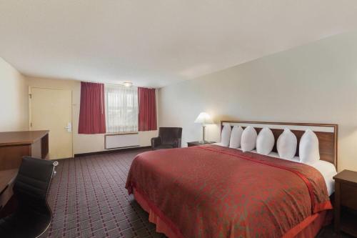 a hotel room with a large bed and a desk at Days Inn by Wyndham Auburn in Auburn