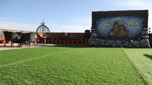 a field of grass with a sign on the side of a building at Hotel Ambrosia, Charikot, dolakha in Charikot