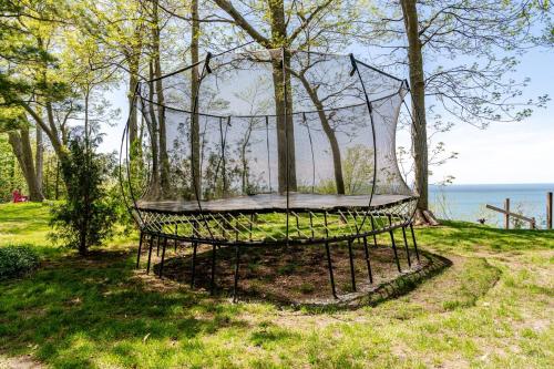 a metal trampoline in the grass near the water at All the Waters Retro Home on Lake Michigan- Your Own PRIVATE BEACH in Benton Harbor