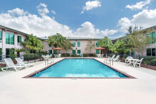 Una piscina en un patio con sillas y un edificio. en Ramada by Wyndham Luling, en Luling