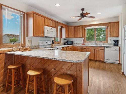 a kitchen with wooden cabinets and a large island with bar stools at 2030 - Horizon`s Summit in Duck