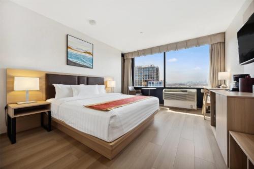 ein Hotelzimmer mit einem Bett und einem großen Fenster in der Unterkunft Ramada by Wyndham Flushing Queens in Queens